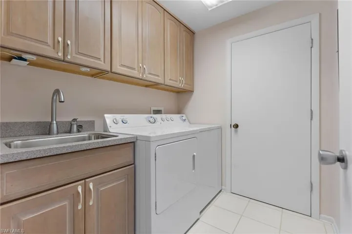 Laundry area featuring cabinet space, light tile patterned floors, and washer and dryer