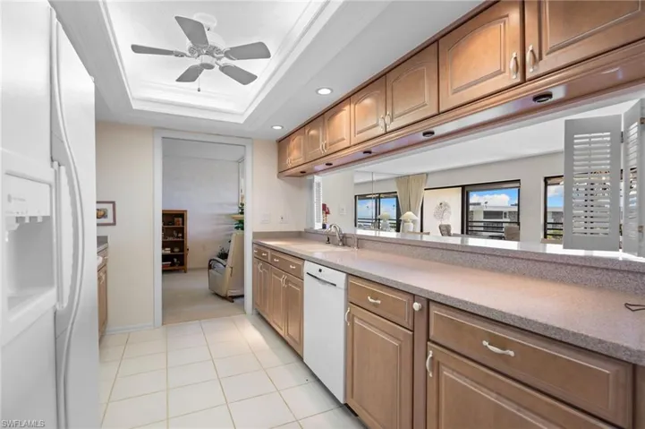Kitchen with white appliances, light stone countertops, recessed lighting, a ceiling fan, and brown cabinets