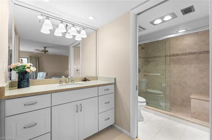 Full bath with vanity, ceiling fan, a shower stall, light tile patterned floors, and connected bathroom