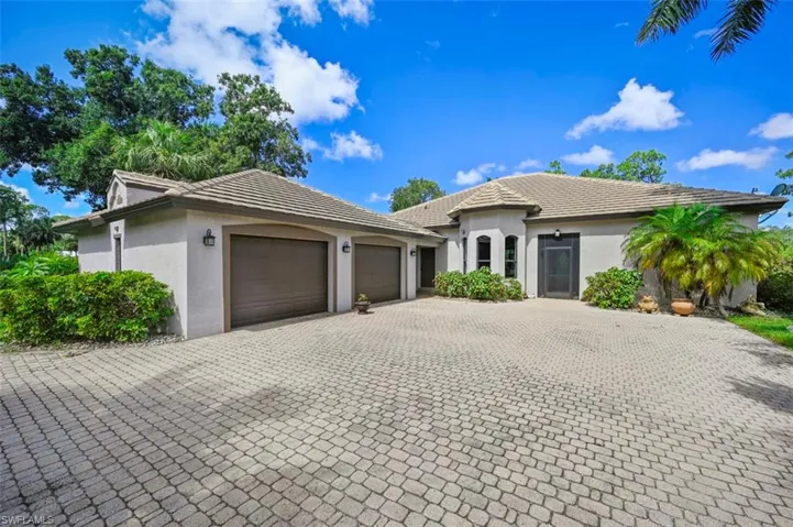 View of front of house with decorative driveway, a garage, stucco siding, and a tile roof