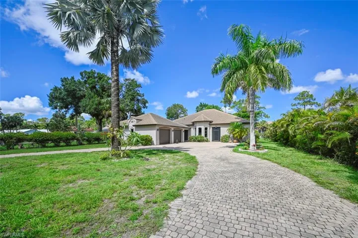 View of front facade featuring a garage, a front yard, decorative driveway, and stucco siding