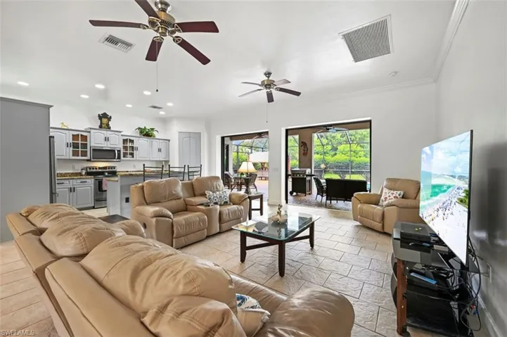 Living room featuring stone tile flooring, recessed lighting, a ceiling fan, and crown molding
