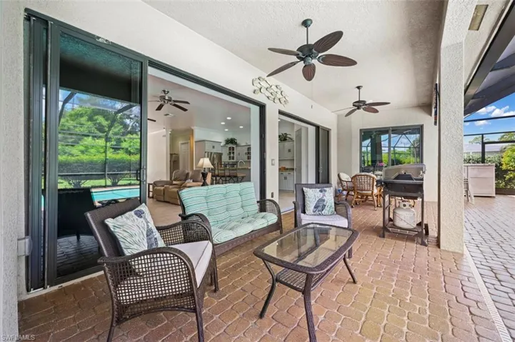 View of patio featuring a ceiling fan, an outdoor living space, glass enclosure, and a grill