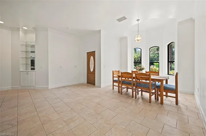 Dining space with ornamental molding, recessed lighting, built in shelves, and a towering ceiling
