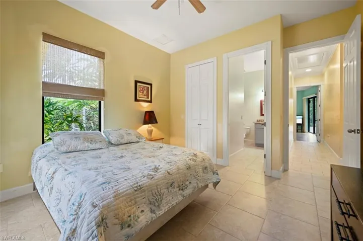 Bedroom featuring a closet, attic access, ceiling fan, and light tile patterned flooring