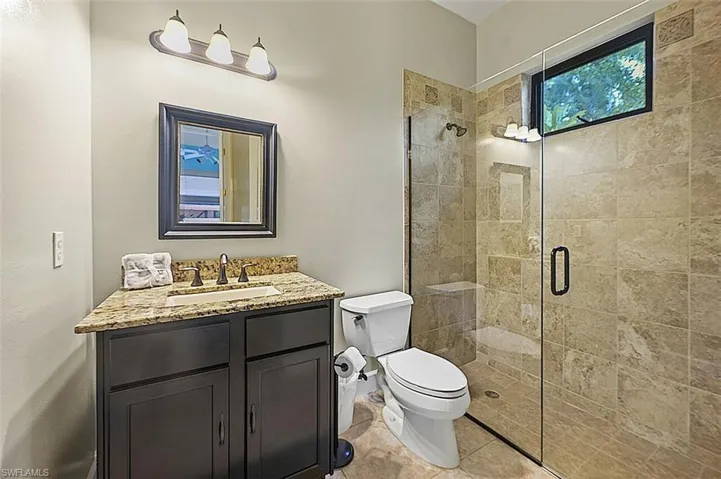 Full bath featuring a tile shower, vanity, and tile patterned flooring