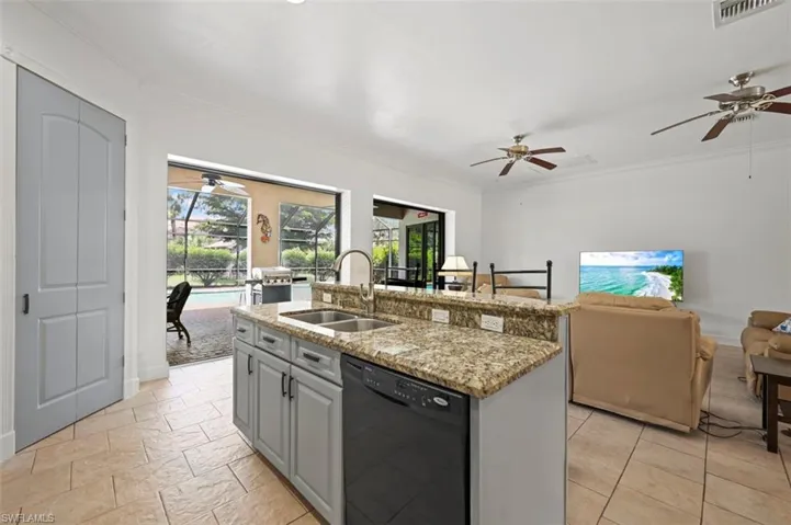 Kitchen featuring black dishwasher, healthy amount of natural light, ceiling fan, crown molding, and open floor plan