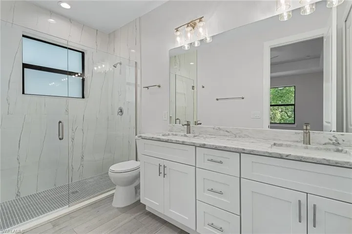 Full bathroom featuring a marble finish shower and double vanity