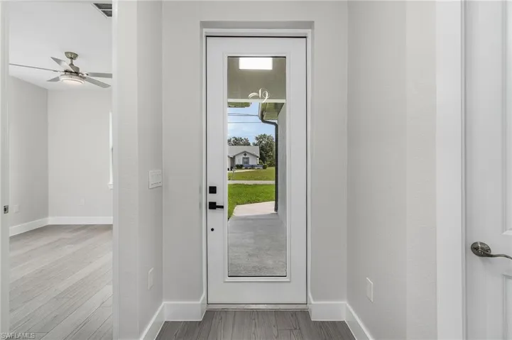 Doorway with wood finished floors and a ceiling fan