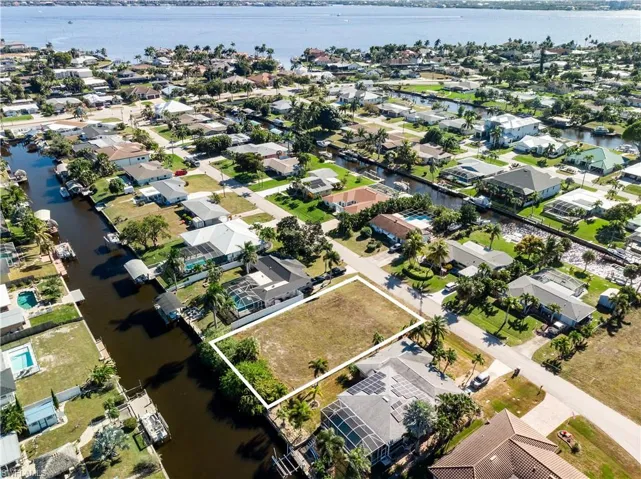 Aerial view of property's location featuring a large body of water, property boundaries highlighted, and nearby suburban area