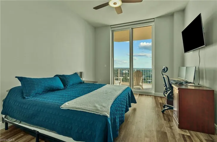 Bedroom featuring wood finished floors, ceiling fan, access to outside, an office area, and floor to ceiling windows