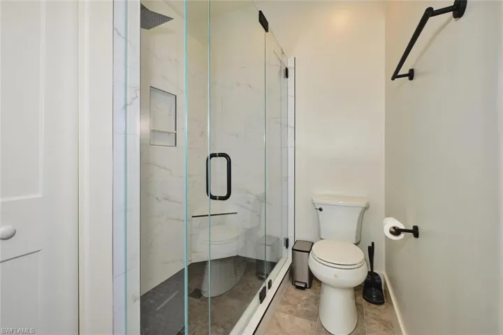 Bathroom featuring toilet and a marble finish shower