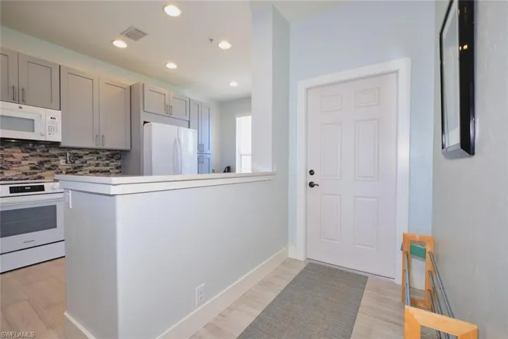 Kitchen featuring white appliances, backsplash, light countertops, recessed lighting, and a peninsula
