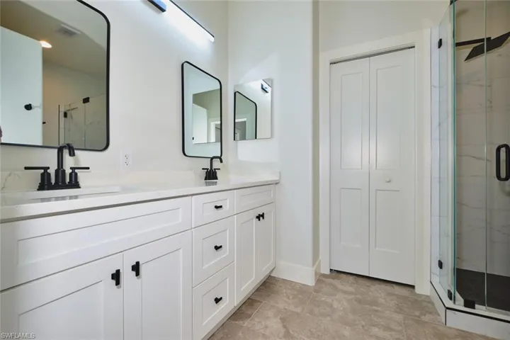 Full bathroom featuring a marble finish shower, double vanity, and a closet