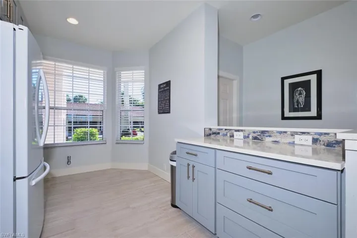 Kitchen featuring freestanding refrigerator, light stone counters, recessed lighting, light wood-type flooring, and gray cabinetry