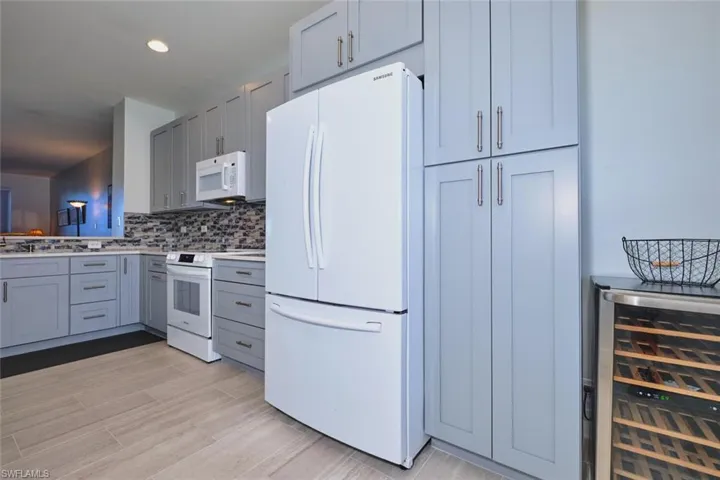 Kitchen featuring white appliances, wine cooler, gray cabinets, tasteful backsplash, and light wood finished floors