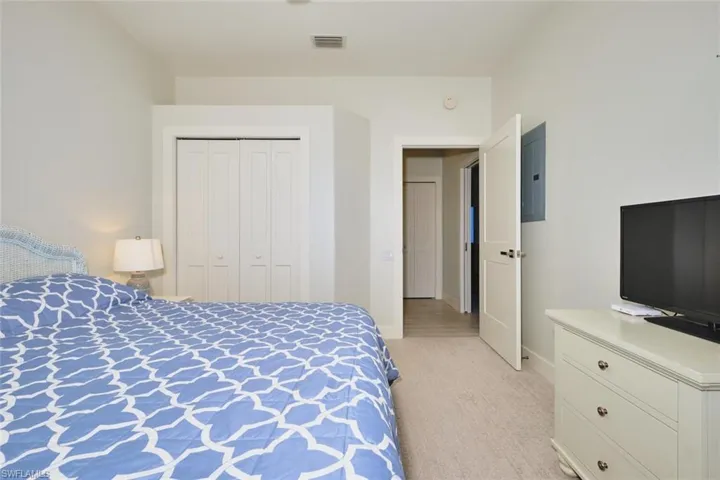 Bedroom with light colored carpet, electric panel, and a closet