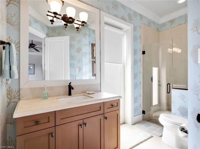 Bathroom with vanity, a stall shower, crown molding, wallpapered walls, and a chandelier