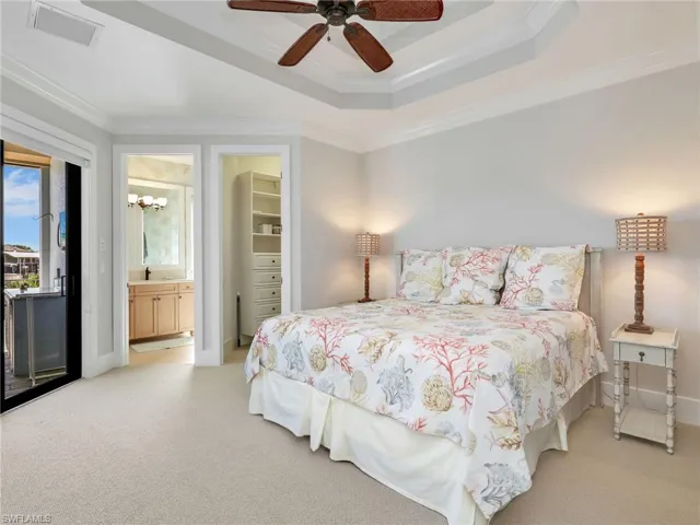 Bedroom featuring a spacious closet, ornamental molding, light carpet, a raised ceiling, and ceiling fan