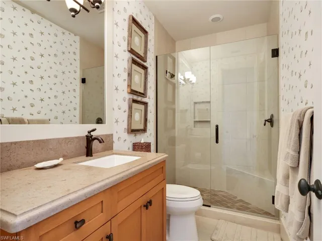 Full bath featuring wallpapered walls, vanity, a stall shower, and a chandelier