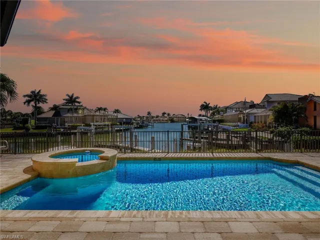 Combined pool / hot tub with a water view and a patio area