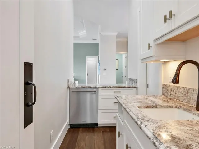 Full bathroom with ornamental molding, dark wood-type flooring, and two vanities