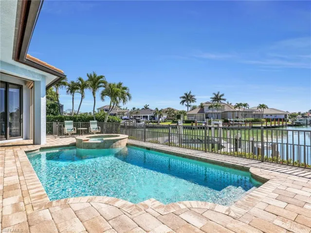 Integrated pool / hot tub with a patio, a residential view, a fenced backyard, and a water view