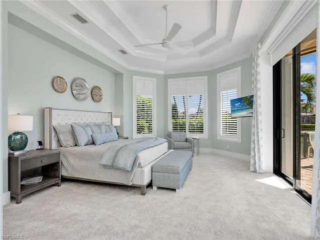 Bedroom with access to exterior, light colored carpet, a ceiling fan, a raised ceiling, and crown molding