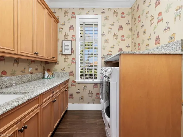 Laundry room featuring washer and dryer, dark wood-type flooring, wallpapered walls, cabinet space, and crown molding