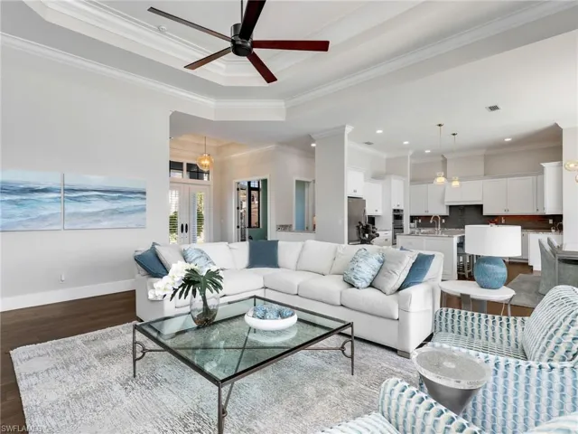 Living room featuring ceiling fan, ornamental molding, french doors, dark wood-style flooring, and a raised ceiling