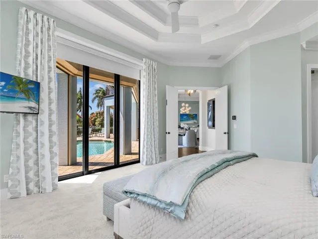 Bedroom with access to outside, carpet, ornamental molding, a ceiling fan, and a tray ceiling