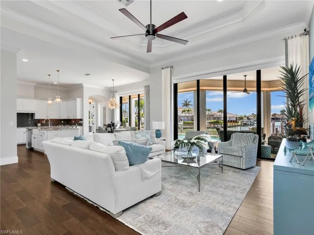 Living area with a ceiling fan, ornamental molding, arched walkways, dark wood finished floors, and a chandelier