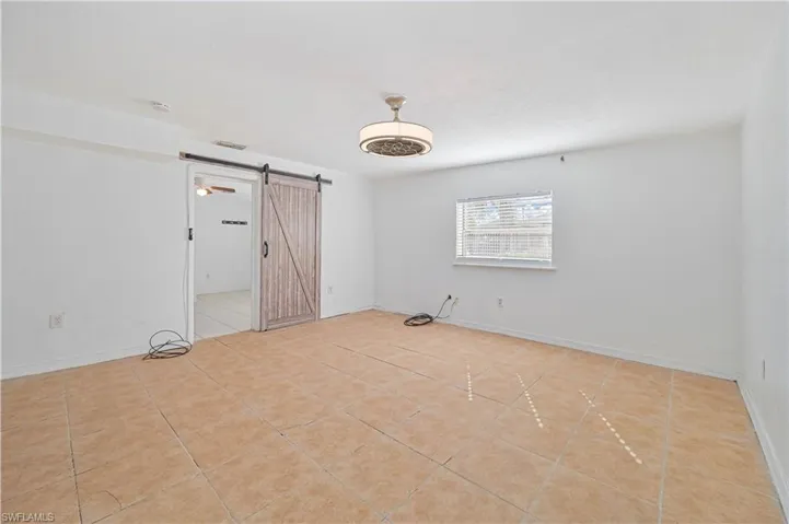 Unfurnished room featuring a barn door and light tile patterned flooring