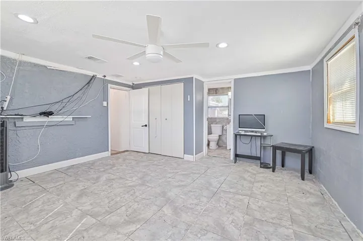 Bedroom with a closet, a ceiling fan, ensuite bath, recessed lighting, and a textured wall