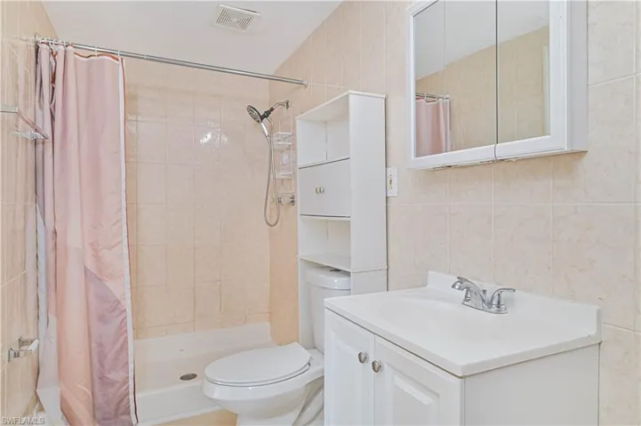 Full bathroom with a shower stall, vanity, and tile walls