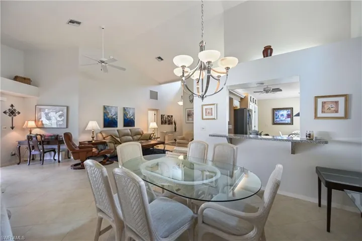 Dining space featuring ceiling fan, a chandelier, high vaulted ceiling, and light tile patterned floors
