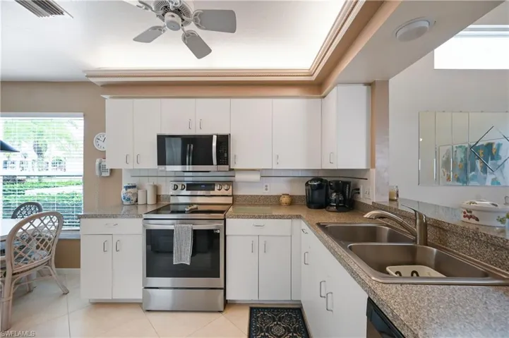 Kitchen featuring healthy amount of natural light, stainless steel appliances, and white cabinets