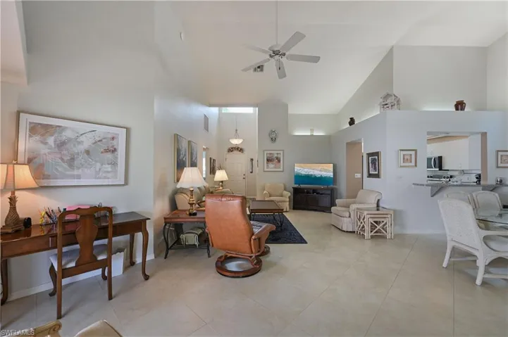 Living area with high vaulted ceiling, ceiling fan, and light tile patterned floors