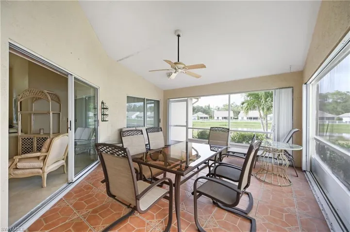 Sunroom featuring vaulted ceiling, a ceiling fan, tile patterned floors, and outdoor dining space