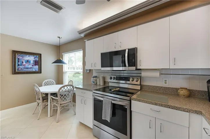 Kitchen with appliances with stainless steel finishes, backsplash, dark countertops, white cabinets, and pendant lighting