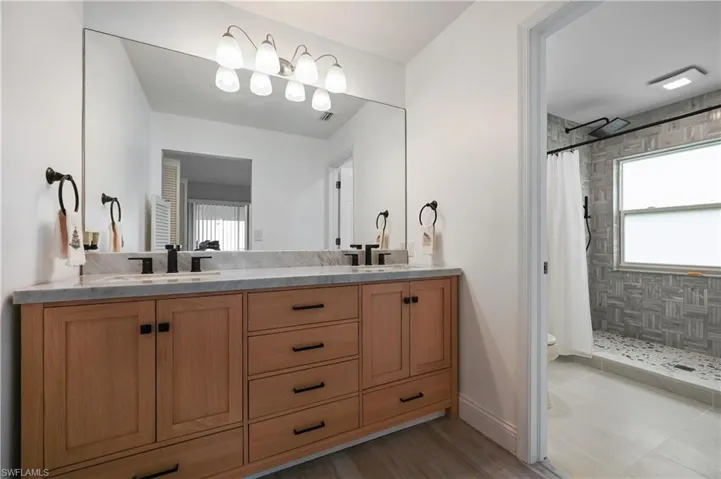 Full bath with double vanity and a shower stall