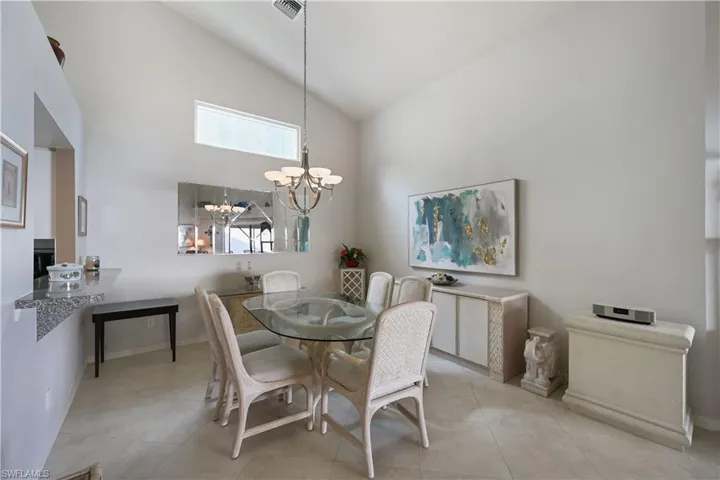 Dining area with high vaulted ceiling, tile patterned floors, and a chandelier