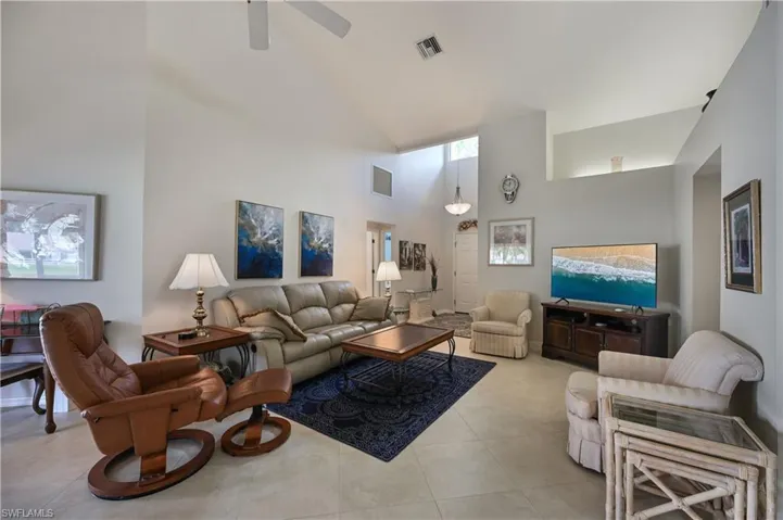 Living room with high vaulted ceiling, light tile patterned floors, and ceiling fan
