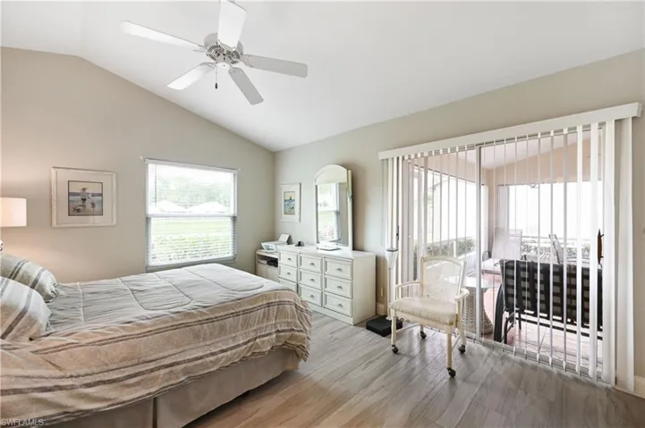 Bedroom with vaulted ceiling, wood finished floors, access to outside, and ceiling fan