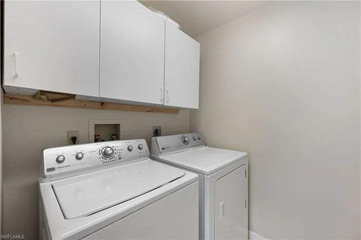 Washroom featuring separate washer and dryer and cabinet space