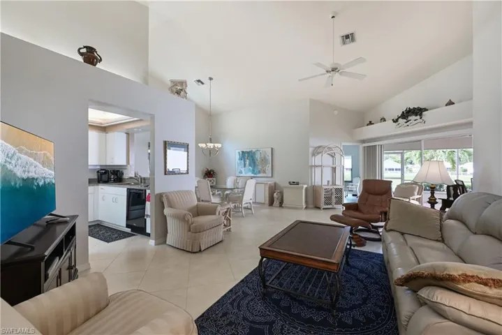 Living area featuring a ceiling fan, high vaulted ceiling, a chandelier, and light tile patterned floors