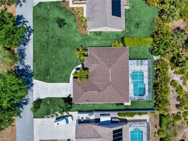 Bird’s-eye perspective showcasing the home, pool, and beautifully landscaped yard.