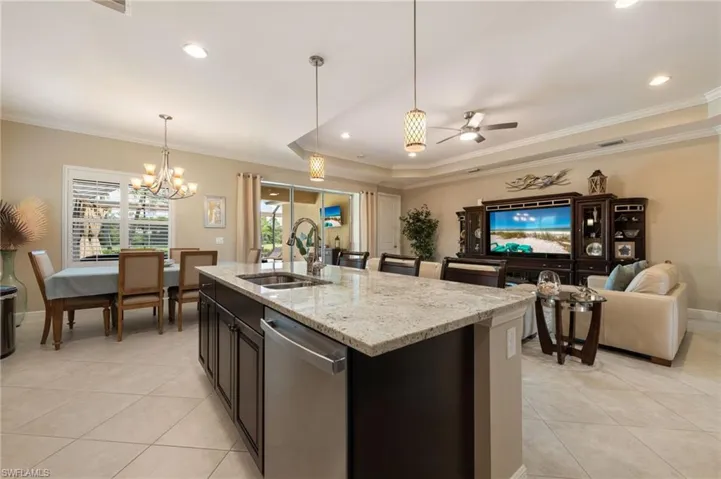 Open-concept living area featuring a kitchen island with stone countertop, stainless steel sink, and dishwasher