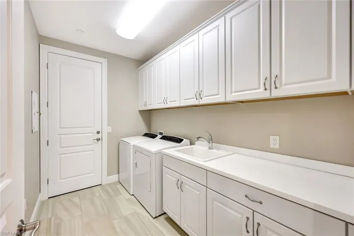 Laundry room with washer and dryer, cabinets, and sink