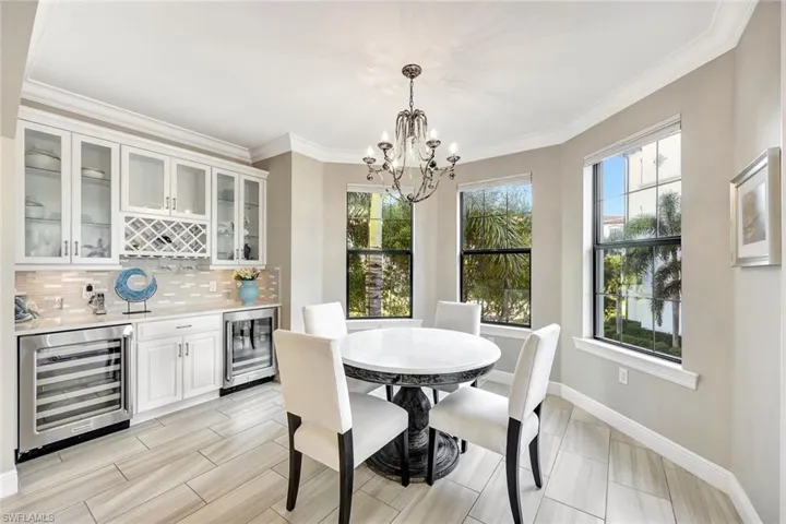 Dining area featuring ornamental molding, beverage cooler, and an inviting chandelier